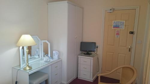 a room with a desk with a mirror and a television at The Belgrave Hotel Tenby in Tenby