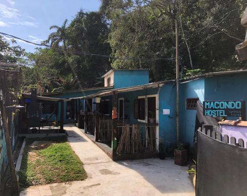 un bâtiment bleu avec une clôture devant lui dans l'établissement Macondo Hostel Itamambuca, à Praia de Itamambuca