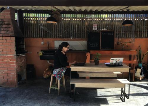 une femme assise à une table avec un ordinateur portable dans l'établissement Macondo Hostel Itamambuca, à Praia de Itamambuca
