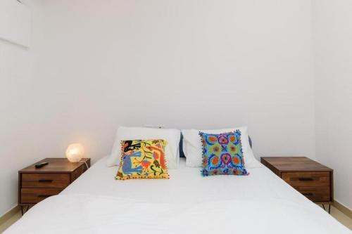 Un dormitorio con una cama blanca con dos almohadas. en Netanyas One Bedroom Beachside Escape, en Netanya