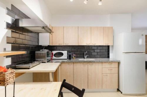 Una cocina con gabinetes de madera y un refrigerador blanco. en Netanyas One Bedroom Beachside Escape, en Netanya