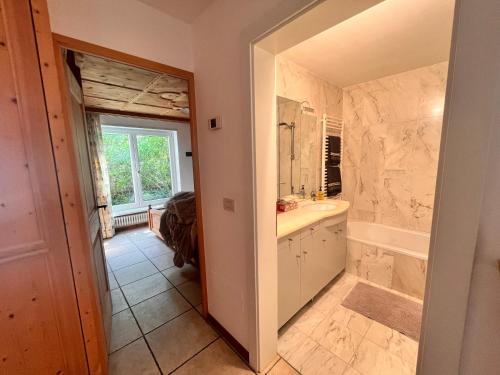 Un baño con bañera, lavabo y espejo. en Traditional Cozy Apartment, en Tirolo