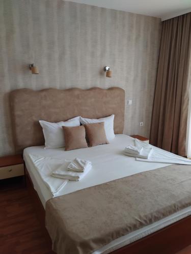 a bedroom with a large bed with two napkins on it at Family Hotel Dayana Beach in Sinemorets