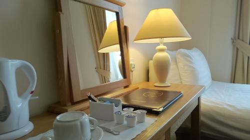 a hotel room with a table with a lamp and a mirror at The Belgrave Hotel Tenby in Tenby