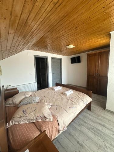 a large bed in a room with a wooden ceiling at CTA House in Cîrţişoara