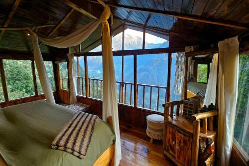 a bedroom with a canopy bed in a room with windows at Parvatis Lap Luxury Hostel & Camps in Kasol