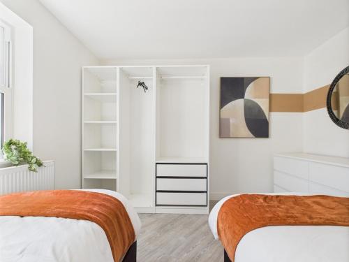 a white bedroom with two beds and a closet at Modern Townhouse Sleeps 6 in Royal Tunbridge Wells