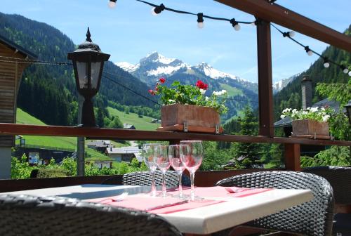 a table with wine glasses and a view of a mountain at Hôtel le Christiania in Arêches-Beaufort