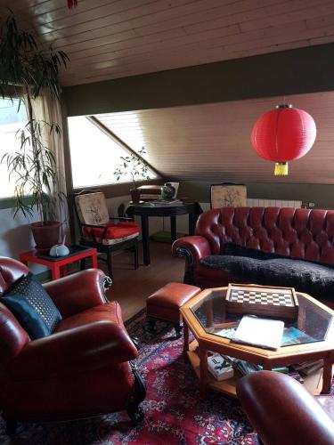a living room with leather couches and a table at Chambre d'hôte - La Maison Verte in Charmes