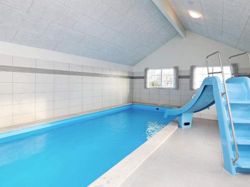 a swimming pool with a slide in a room with a swimming pool at 26 person holiday home in Frørup in Frørup