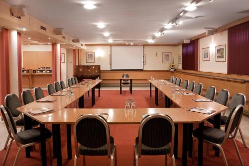 a conference room with tables and chairs and a whiteboard at Hotel Kálvária in Győr