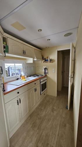 a kitchen with white cabinets and a wooden floor at Mobilehome in Weissenburg