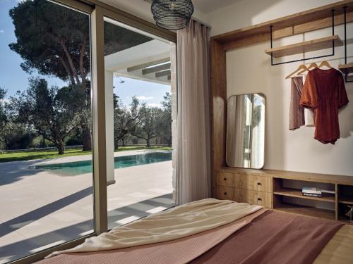 Un dormitorio con una gran puerta de cristal con vistas a una piscina. en Aura by Vintage Travel, en Vasilikos