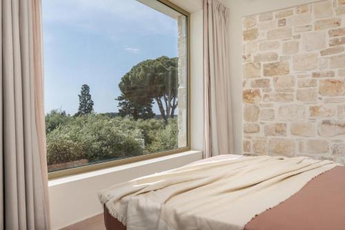 Un dormitorio con una gran ventana con una pared de piedra. en Aquatic by Vintage Travel, en Vasilikos