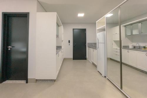 a hallway with a black door in a white kitchen at Seu apê ideal te espera! CA1306 in Maringá