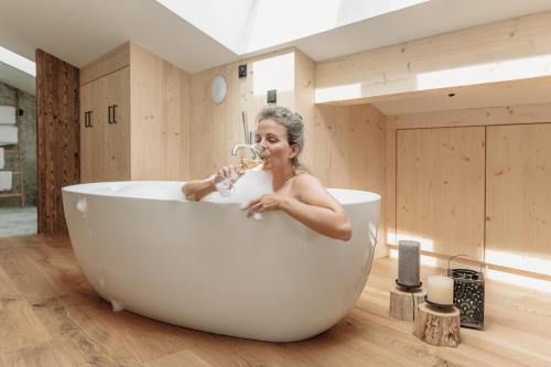 una donna è seduta in una vasca da bagno e beve di grainau1 boutique apartments a Grainau