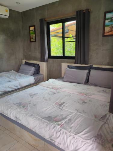 two twin beds in a room with a window at Ban Rim Nam Klongwan in Klong Wan