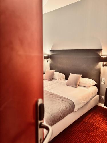 a bedroom with a bed with a black headboard at Logis Hôtel Saint Martin in Orléans