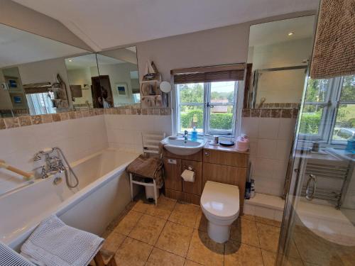 a bathroom with a tub and a toilet and a sink at The Old Post Office B&B in Lymm
