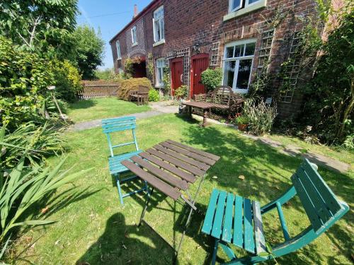 two blue chairs and a wooden table in a yard at The Old Post Office B&B in Lymm
