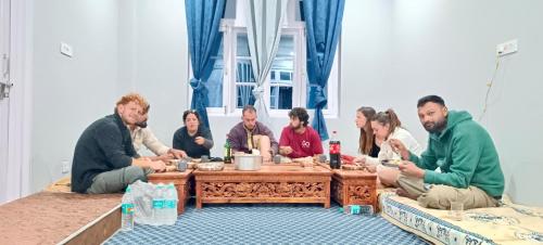 a group of people sitting around a wooden table at Stargazing Homestay Nako in Nako