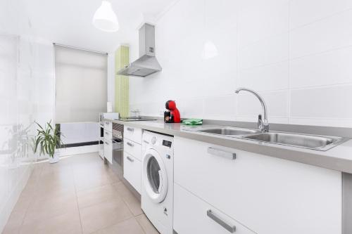 a white kitchen with a sink and a dishwasher at Home2Book Modern Apartment Near Playa del Pozo in Puerto del Rosario
