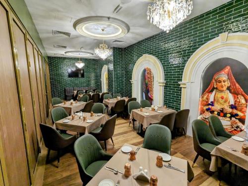 a restaurant with tables and chairs and a picture of a woman at Dubai Grand Hotel by Fortune, Dubai Airport in Dubai