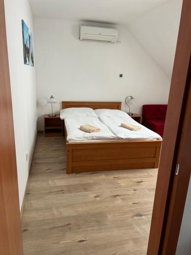 a bedroom with a bed with white sheets and wooden floors at Penzion Kosík Tvrdonice in Tvrdonice