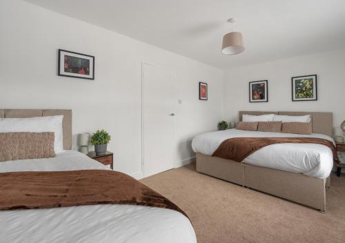 two beds in a bedroom with white walls at The Grand Southampton Stay, Sleeps 12 in Southampton