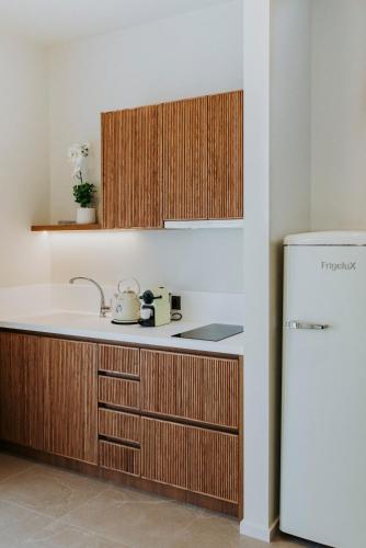 a kitchen with wooden cabinets and a white refrigerator at Volaka Luxury Suites in Kos Town
