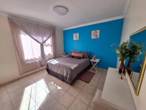 a bedroom with blue walls and a bed and a window at MV self-catering 3 Units in Bloemfontein