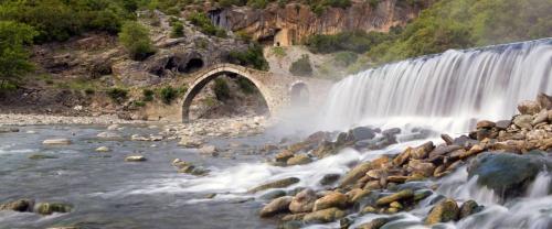 a waterfall over a river with a bridge at The Mosaic House - Shtepia me Mozaik in Përmet