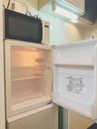 an open refrigerator with a microwave on top of it at Shinjuku city西新宿 in Tokyo