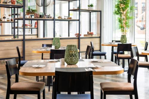a restaurant with wooden tables and chairs and windows at Best Western Plus Hotel Papenburg in Papenburg