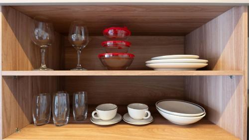 a wooden cabinet with dishes and wine glasses at By DH: Luxo e conforto em Perdizes, aos poucos minutos do Allianz parque in Sao Paulo