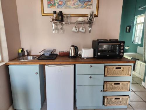 a kitchen with a counter with a microwave and a sink at Greyton Toad Hall exclusive use up to 18 and by supplement up to 22 with massive pool and hot tub and sometimes we rent individual rooms in Greyton