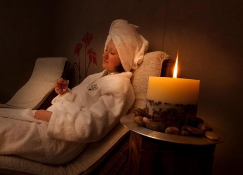 a baby in a bath towel sitting in a chair next to a candle at Vaihmalan Hovi in Lempäälä