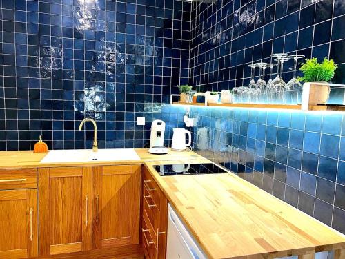 a blue tiled kitchen with a sink and a counter at Séjour Insolite ,SPA SAUNA parking gratuit in Troyes