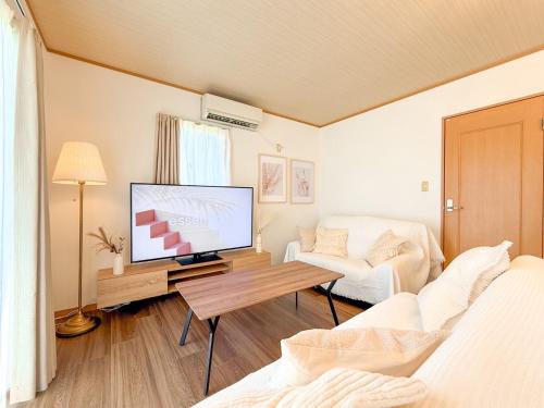 a living room with a tv and a couch at KATAYAMA Base in Takasaki