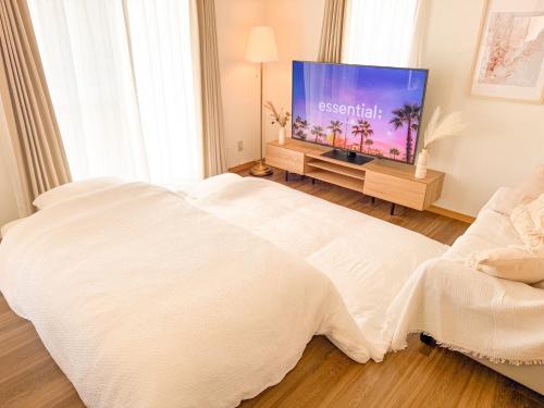 a bedroom with a bed and a flat screen tv at KATAYAMA Base in Takasaki