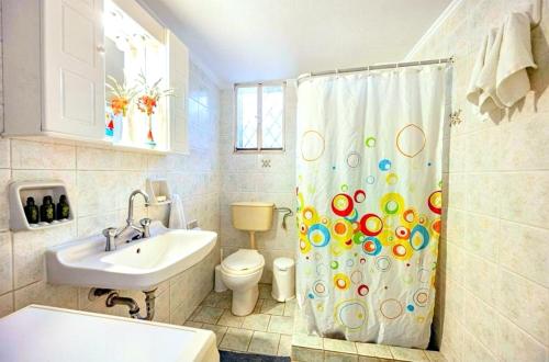 a bathroom with a sink and a shower curtain at Amoni House- An authentic village stay in Pyrgos