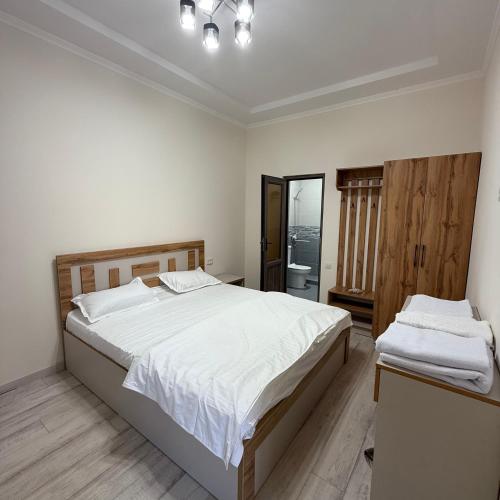 a bedroom with a large bed with white sheets at Nurata Ecotourism Guesthouse in Yukary-Ukhum