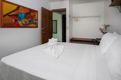 a white bed in a room with a painting on the wall at Villas Jacquelina in Quepos