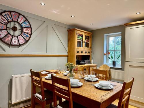 a dining room with a table and a clock on the wall at 2Bed Cottage Near Odiham Castle Scenic Field Views in Greywell
