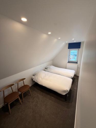 a small bedroom with two beds and two chairs at The Farm Cottage in Waregem