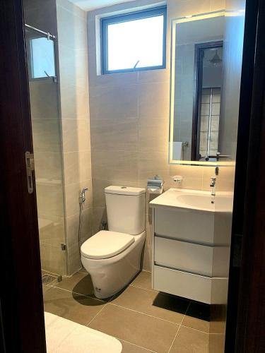 a bathroom with a toilet and a sink and a window at Stylish 2-Bedroom Trizen Retreat in Prime Location in Colombo