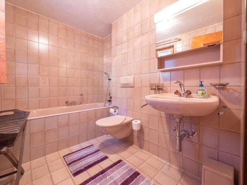 a bathroom with a sink and a toilet and a tub at Duplexwohnung in den Alpen in Riederalp