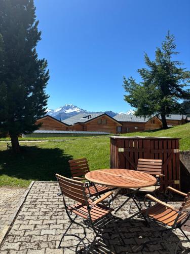 a wooden table and chairs with a table and some trees at Duplexwohnung in den Alpen in Riederalp