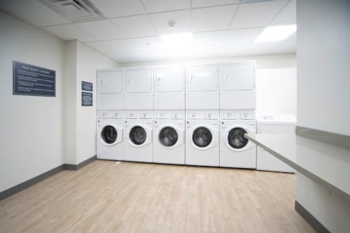 a laundry room with three washing machines and a counter at Candlewood Suites Middletown - Goshen by IHG in Middletown