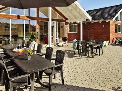 a patio with tables and chairs and an umbrella at Luxury Pool Retreat in Nordborg - By Traum Ferienwohnungen in Nordborg